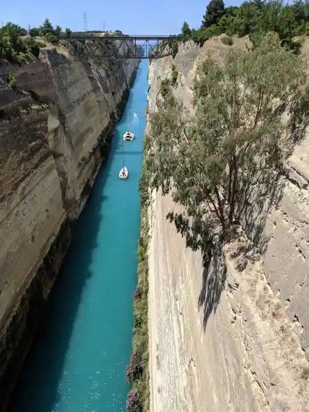 View of the Corinth Canal with turquoise water, sailboats, and rugged limestone cliffs